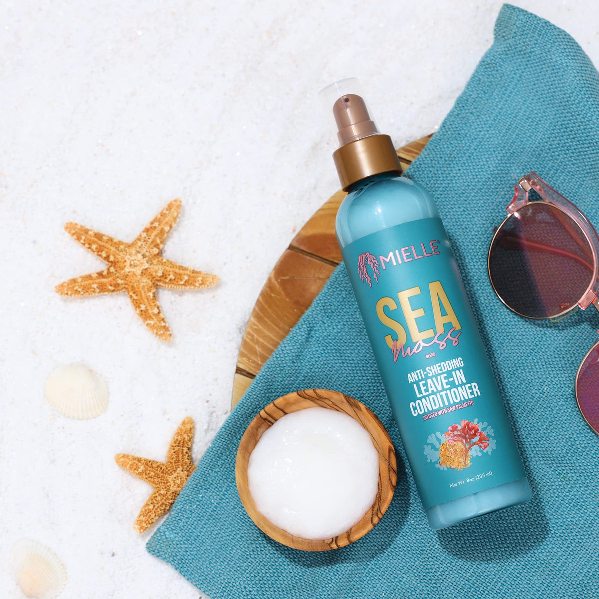 Mielle Organics bottle beside towel and brush in bathroom routine setup
