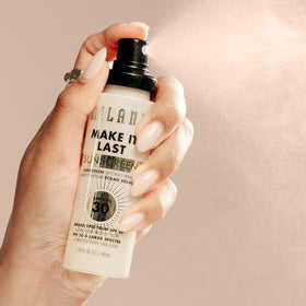 Milani bottle beside foundation to show compatibility with makeup routines
