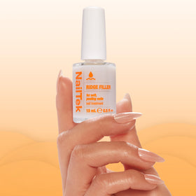 Nail Tek bottle held in hand to show 0.5 fl oz scale and travel-friendly size