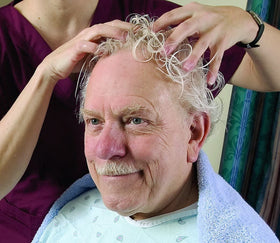 Caregiver applying No-Rinse CleanLife shampoo bedside for gentle, waterless cleansing benefit