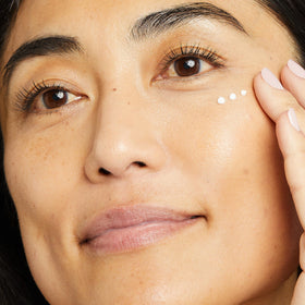 No7 0.5 oz eye cream beside fingertip to show compact size and easy application