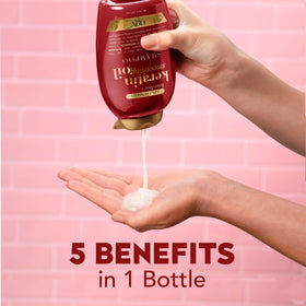 OGX 13 fl oz bottle beside hand for clear size comparison