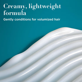 OGX conditioner in hand being dispensed for easy application and control