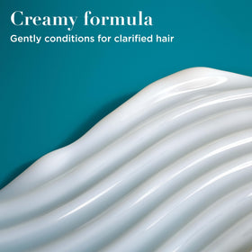 OGX conditioner being applied to wet hair to show clarifying use