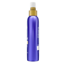 Model using OGX spray while blow-drying for smoother, shinier hair