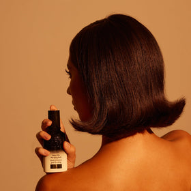 Oribe Balm D'Or 3.4 oz next to hand to show scale and travel-friendly styling portion