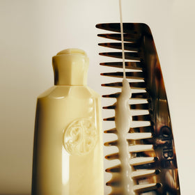 ORIBE bottle in shower setting suggesting moisture-locking routine benefit