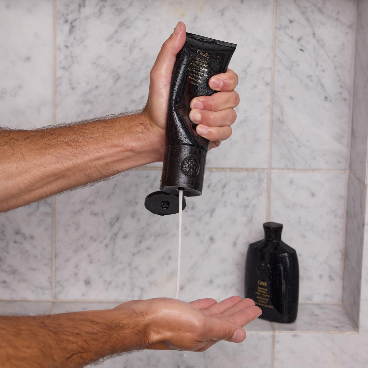 Oribe conditioner held in hand for size comparison and travel-friendly convenience