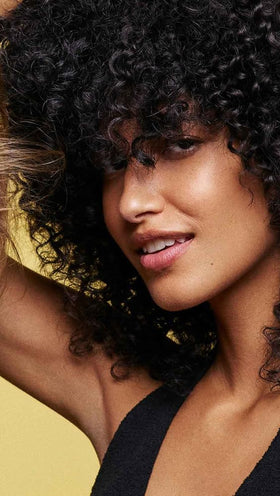 Model using Oribe conditioner during salon-style blowout for smoother hair