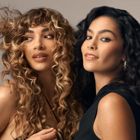 Oribe Curl Shaping Mousse beside hand for scale showing compact 5.7 fl oz size
