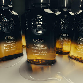 Hand holding Oribe Gold Lust to show scale and travel-friendly size benefit