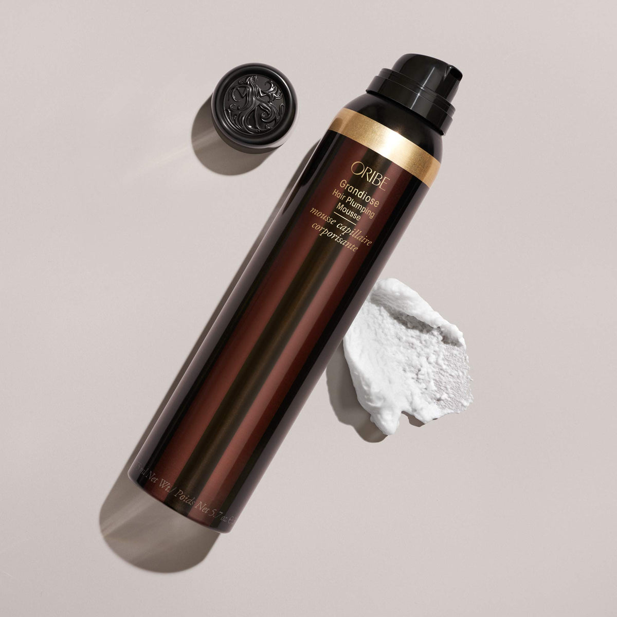 Oribe Grandiose can next to a hand for scale, brand and size clear for shopper confidence