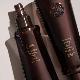 Hand holding Oribe Maximista bottle showing scale and travel-ready convenience