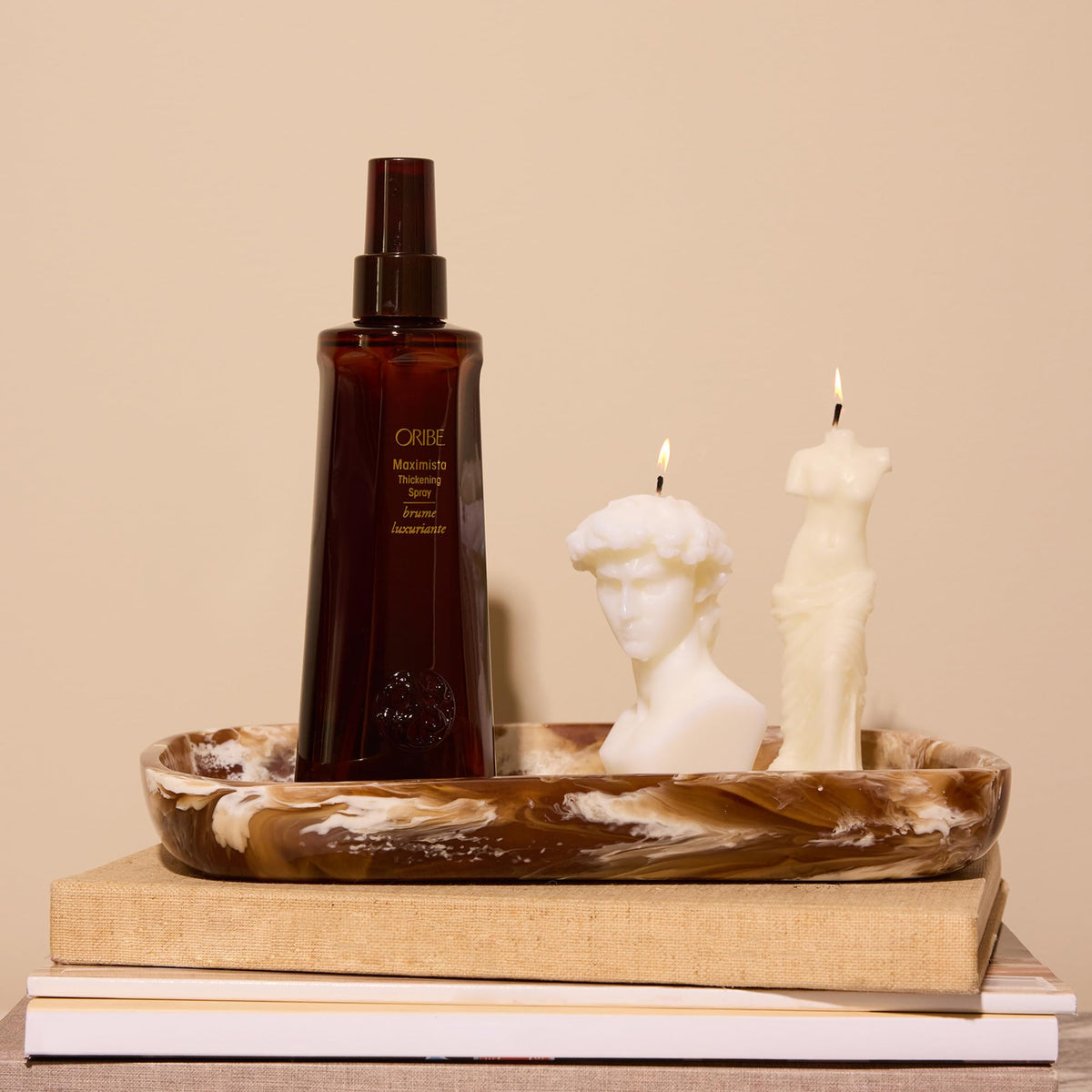 Model styling hair with Oribe Maximista for added volume and heat protection