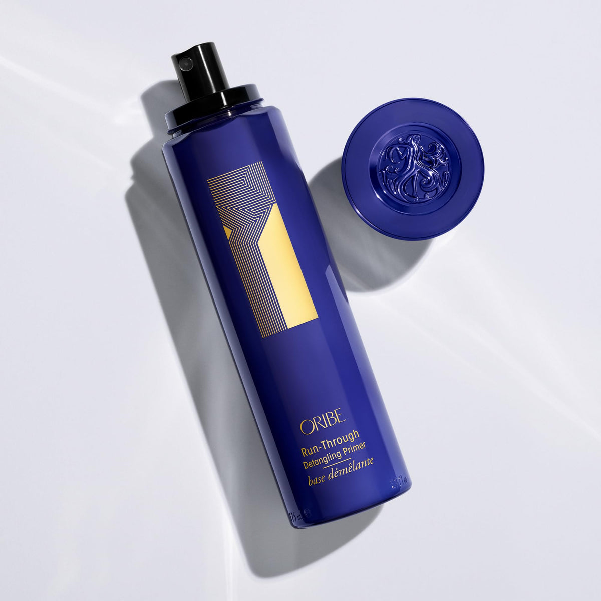 Hand applying ORIBE primer before blow-drying to reduce tangles and protect hair benefit