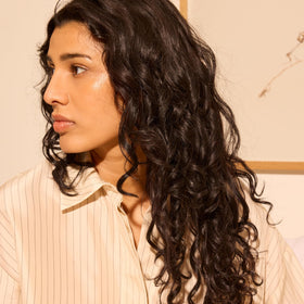Oribe 5oz bottle in hand to show size and travel-friendly benefit