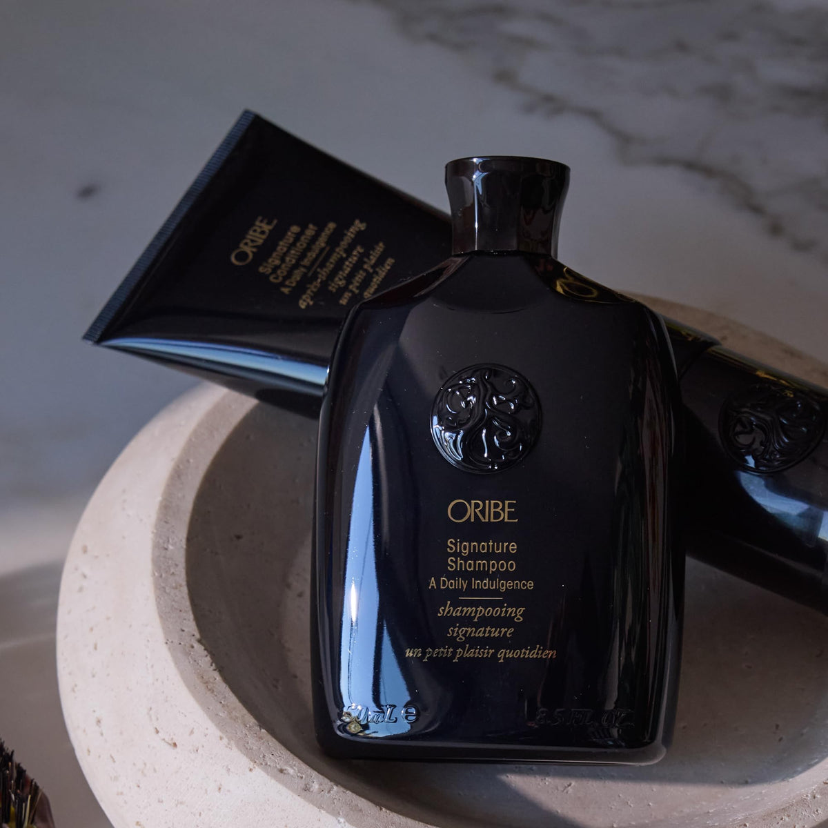 Oribe signature shampoo on vanity with styling tools suggesting salon results