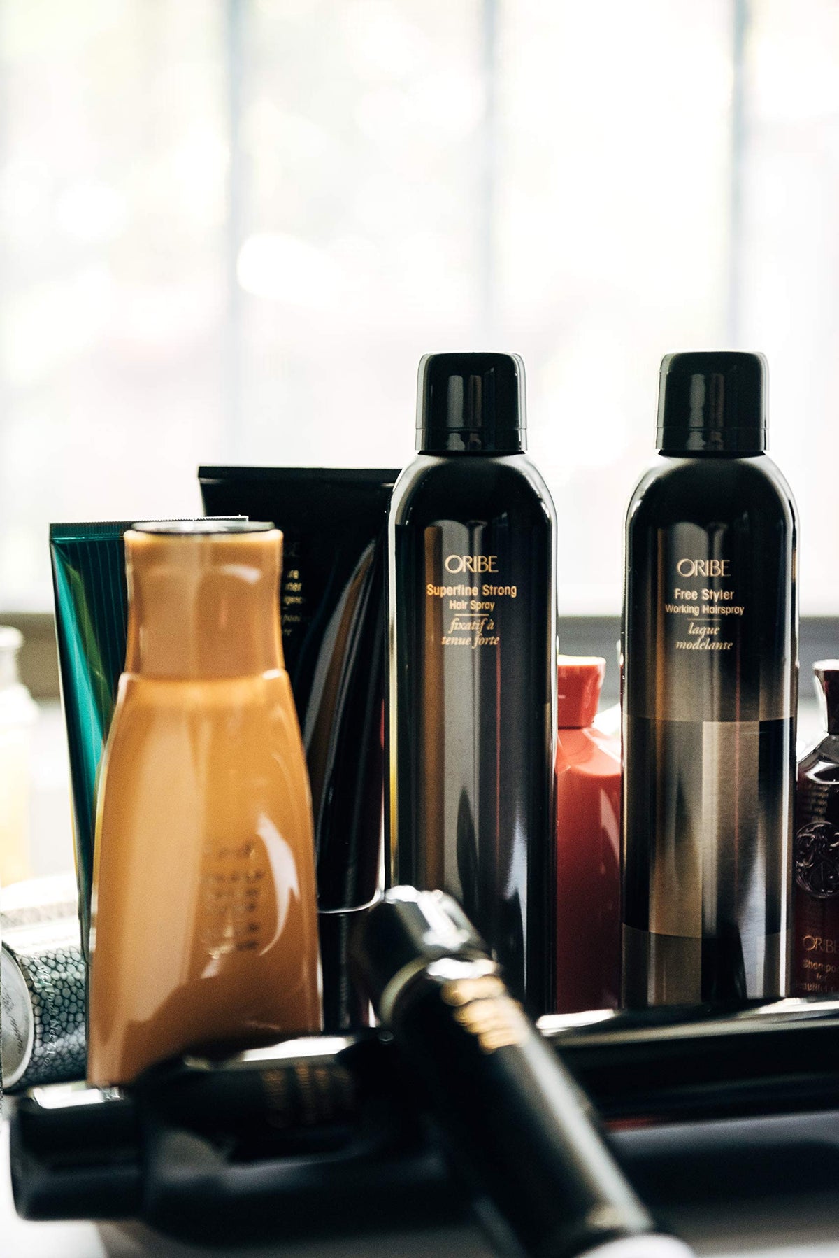 Stylist using Oribe Superfine Strong to set an updo with long-lasting control