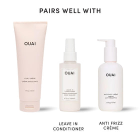 OUAI curl cream next to a hand for scale, easy-to-carry 8 oz size