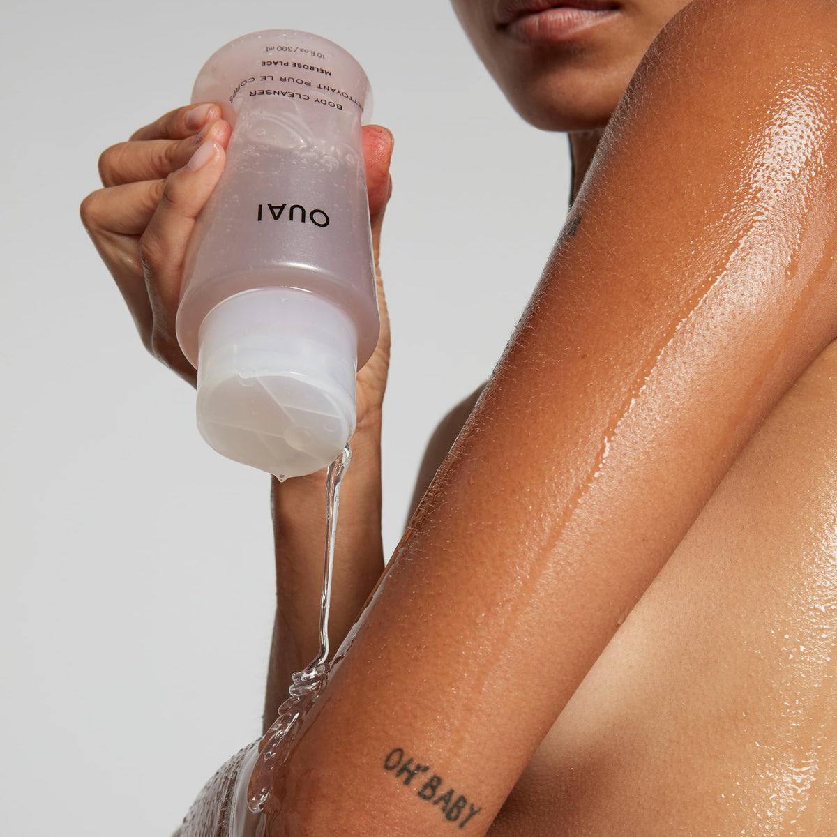 OUAI product poured on loofah showing exfoliation-ready lather benefit