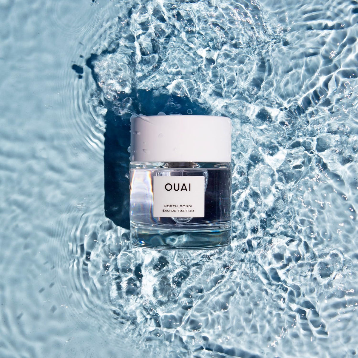 OUAI North Bondi next to everyday items showing 1.7 oz scale for travel convenience