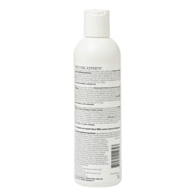 Ouidad bottle next to hand for scale indicating compact 8.5 fl oz travel-friendly size
