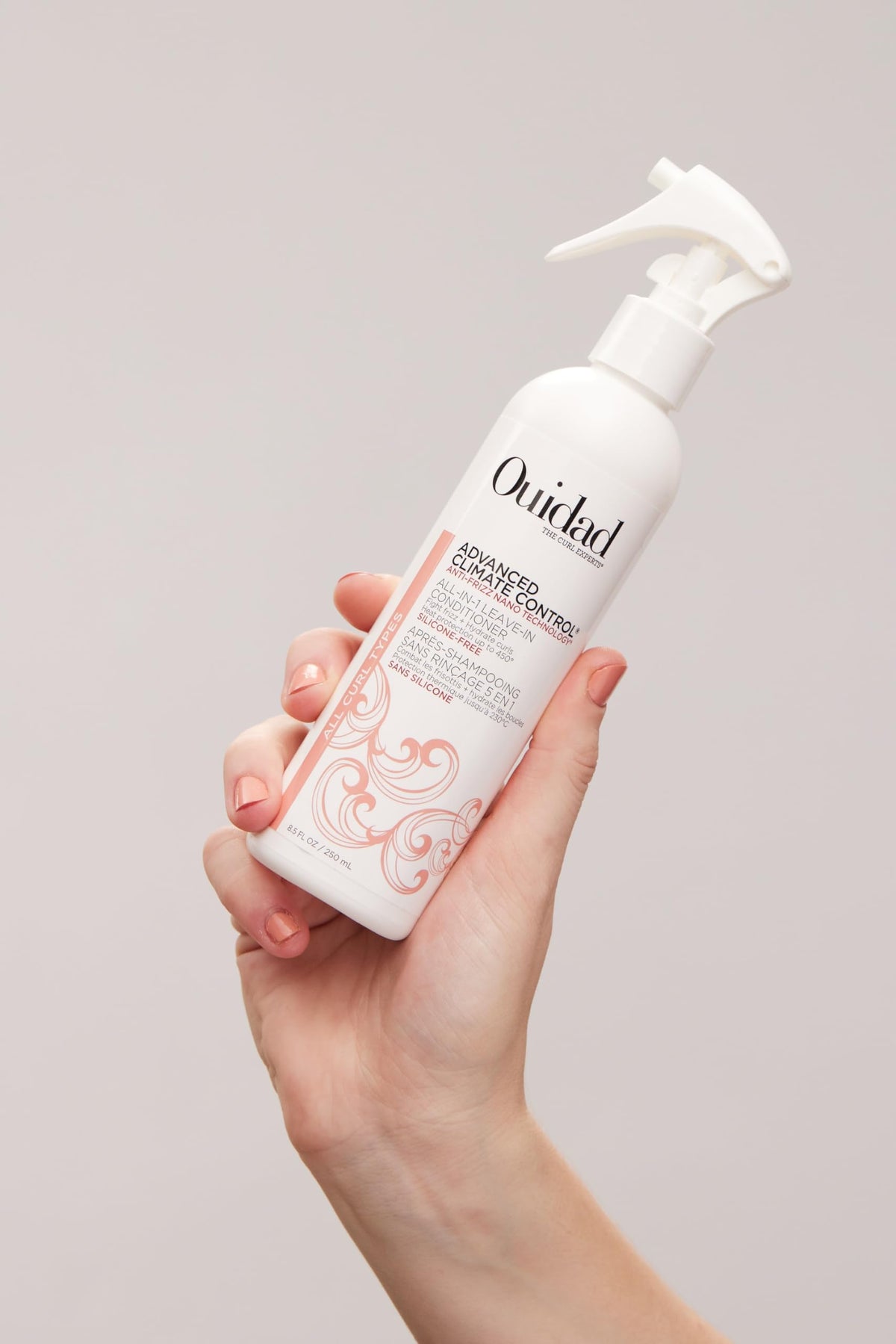 Ouidad 8.5 fl oz bottle beside common items to show travel‑friendly size