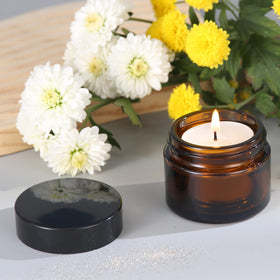 Over News jar filled with cream in hand showing protective amber glass benefit