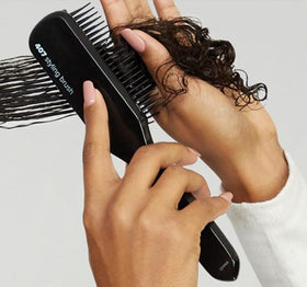 Paul Mitchell Pro Tools brush in hand to show scale and comfortable ergonomic handling