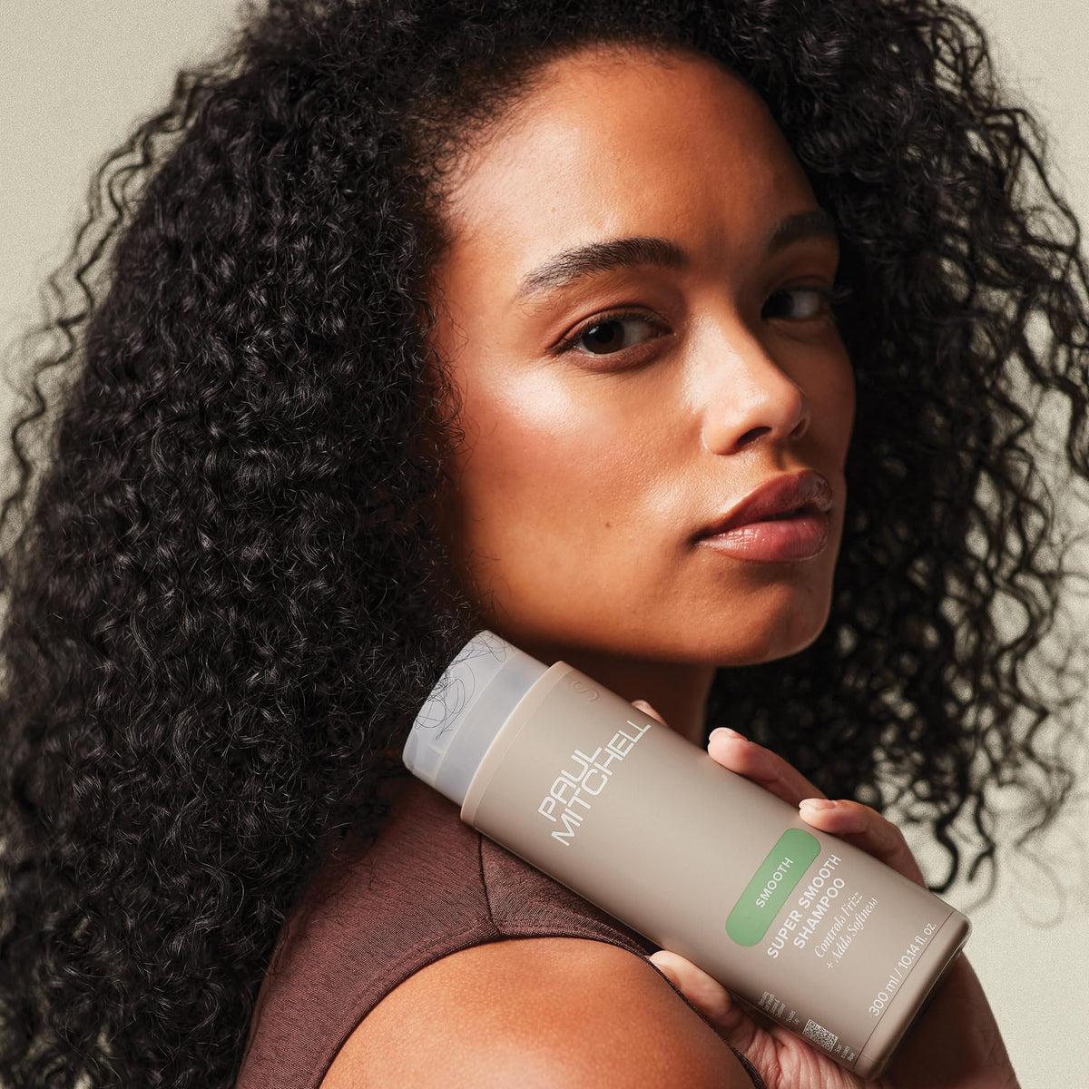 Hand holding Paul Mitchell 10.14 fl oz bottle illustrating size and portability