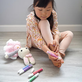 Piggy Paint pens held in child's hand illustrating easy grip for small hands