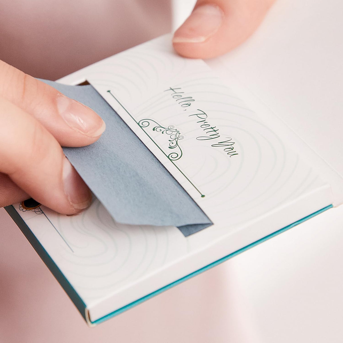 PleasingCare dispenser opened with single blotting sheet being pulled out for sanitary use