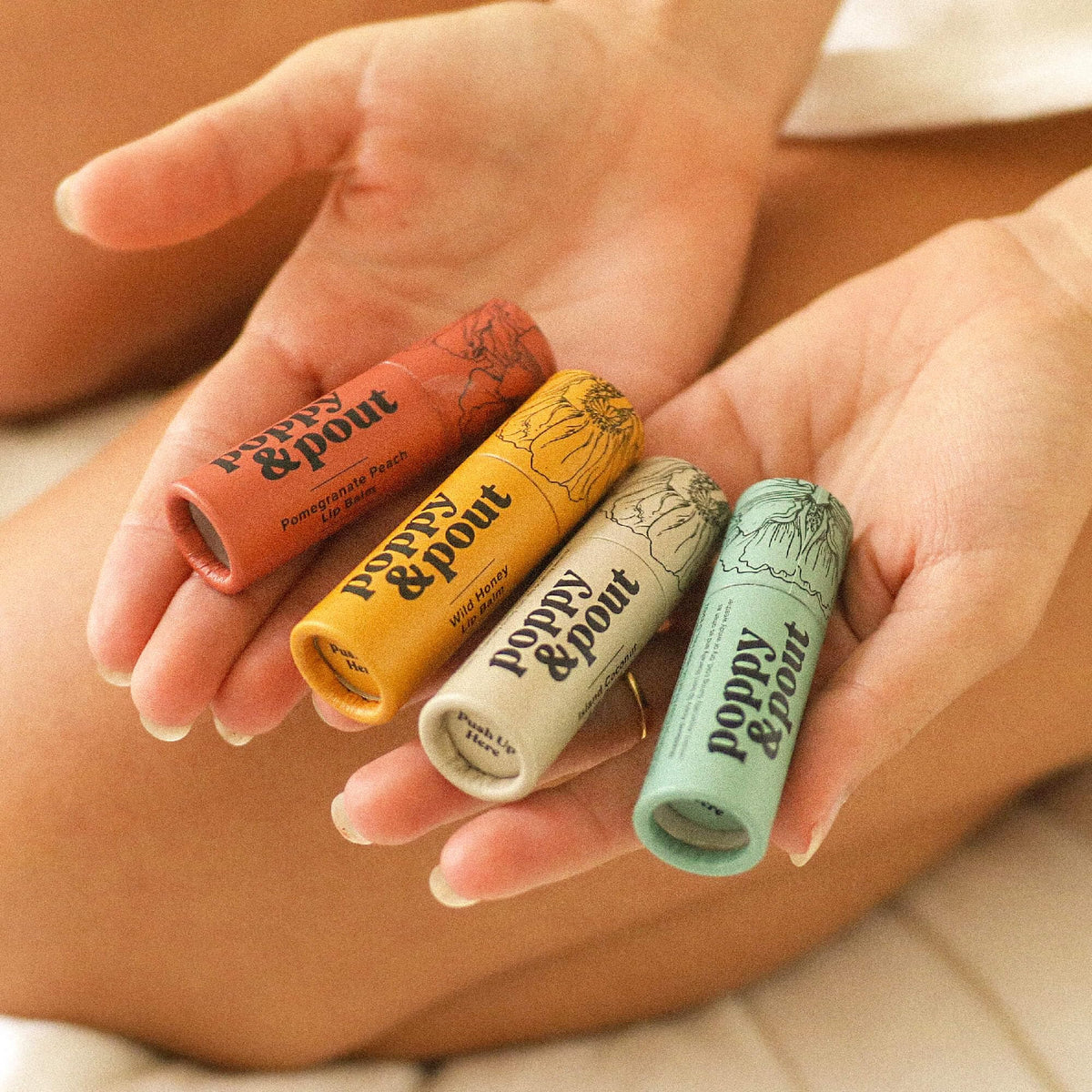 Poppy & Pout inside a beach purse suggesting travel-ready tropical lip care