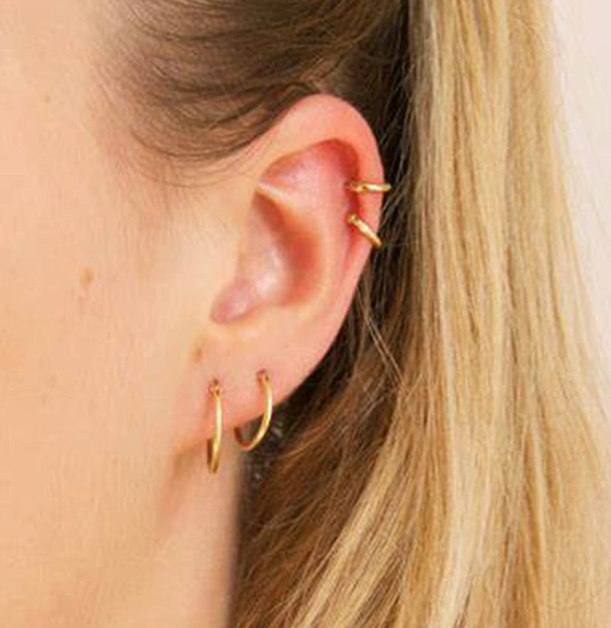 QWALIT piercing gun demonstration on earlobe showing controlled placement and quick piercing