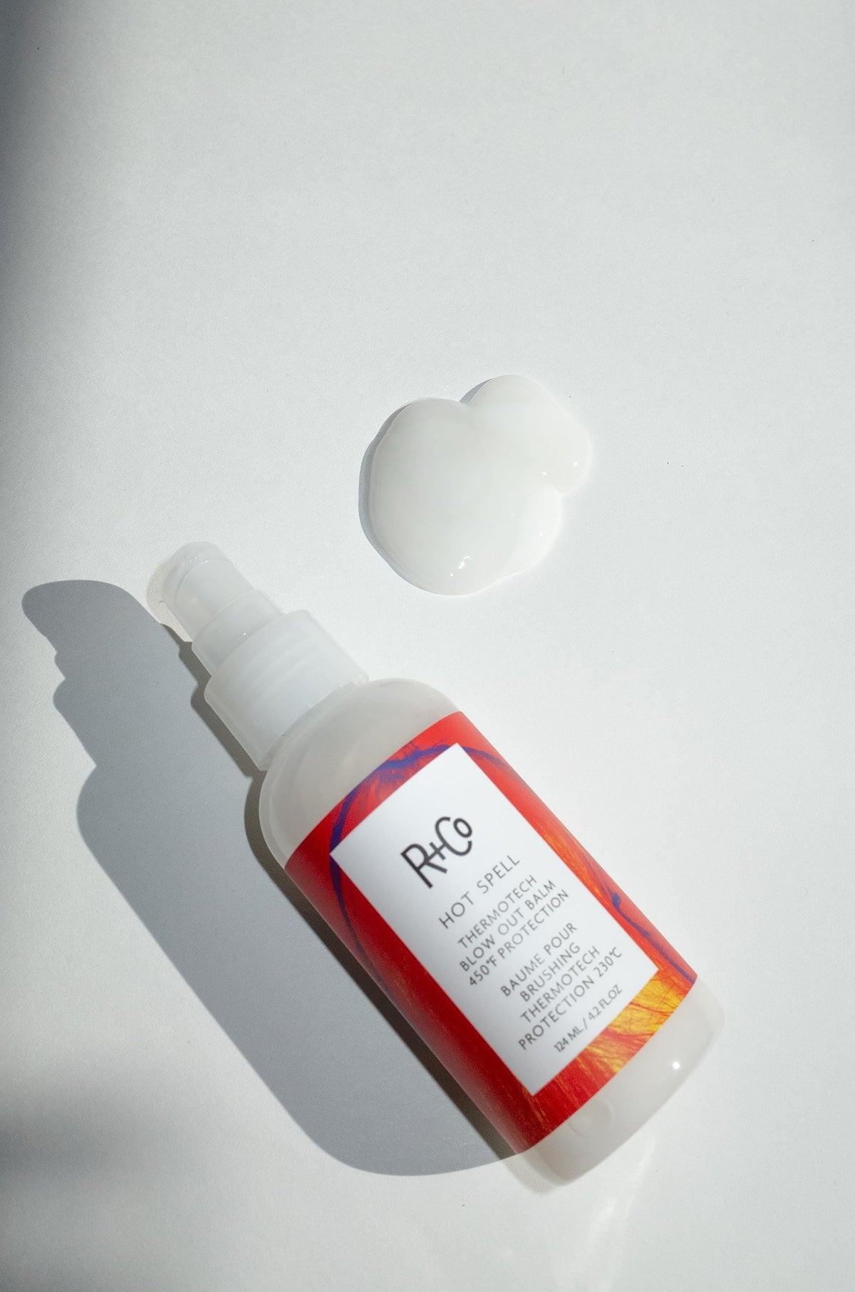 R+Co Hot Spell texture close-up of balm turning creamy, shows silky slip and easy spread