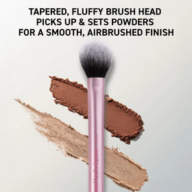 Real Techniques brush applying powder under eye to set concealer and reduce shine for longevity