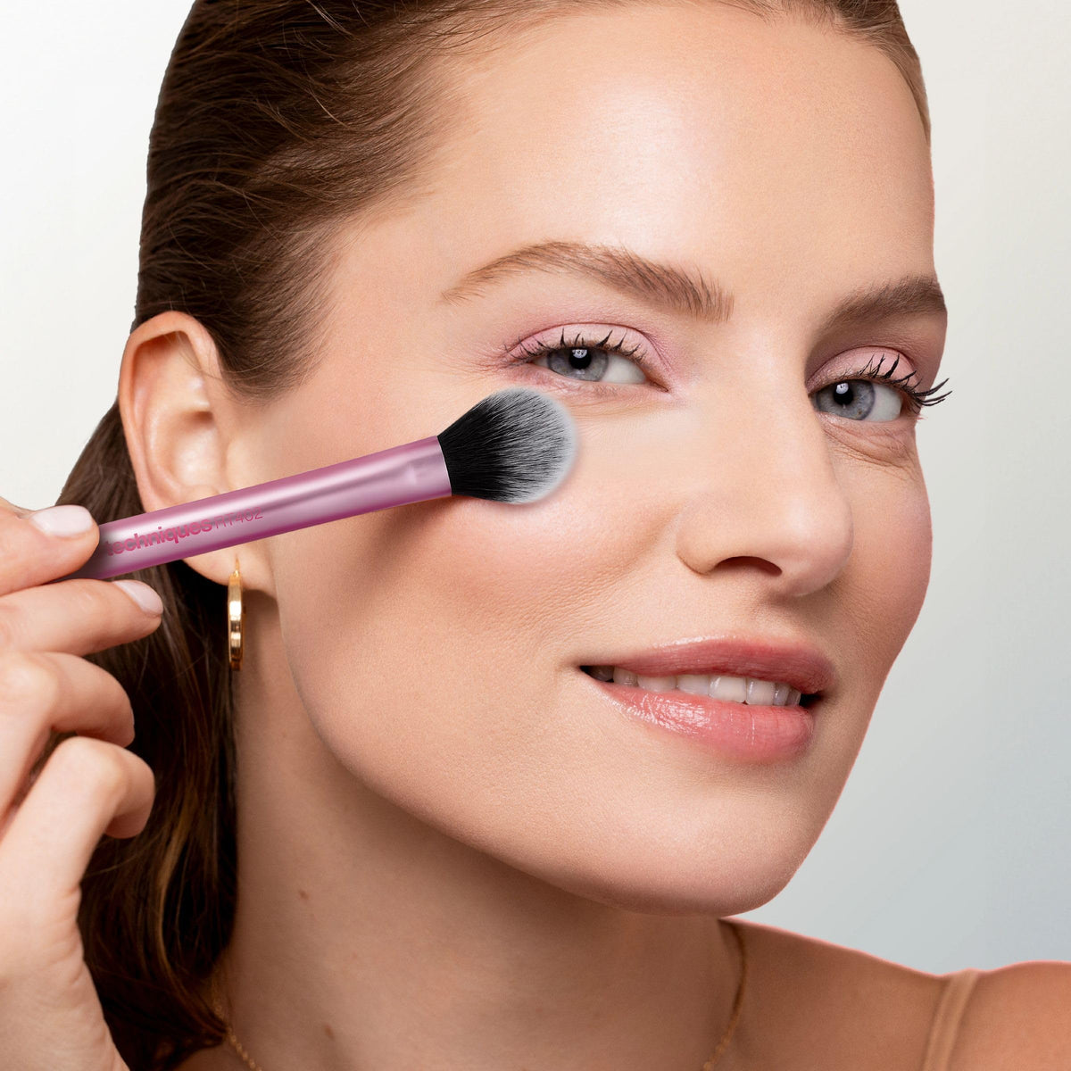 Real Techniques brush on vanity near powders and highlighter suggesting everyday finishing use