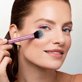 Real Techniques brush on vanity near powders and highlighter suggesting everyday finishing use