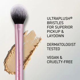 Real Techniques brush held in hand for scale to show compact size and travel-friendly design
