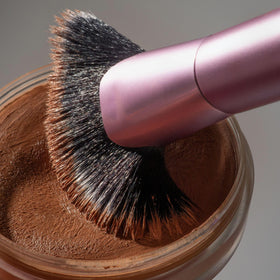 Real Techniques brush in hand applying bronzer to cheek to demonstrate targeted sculpting benefit