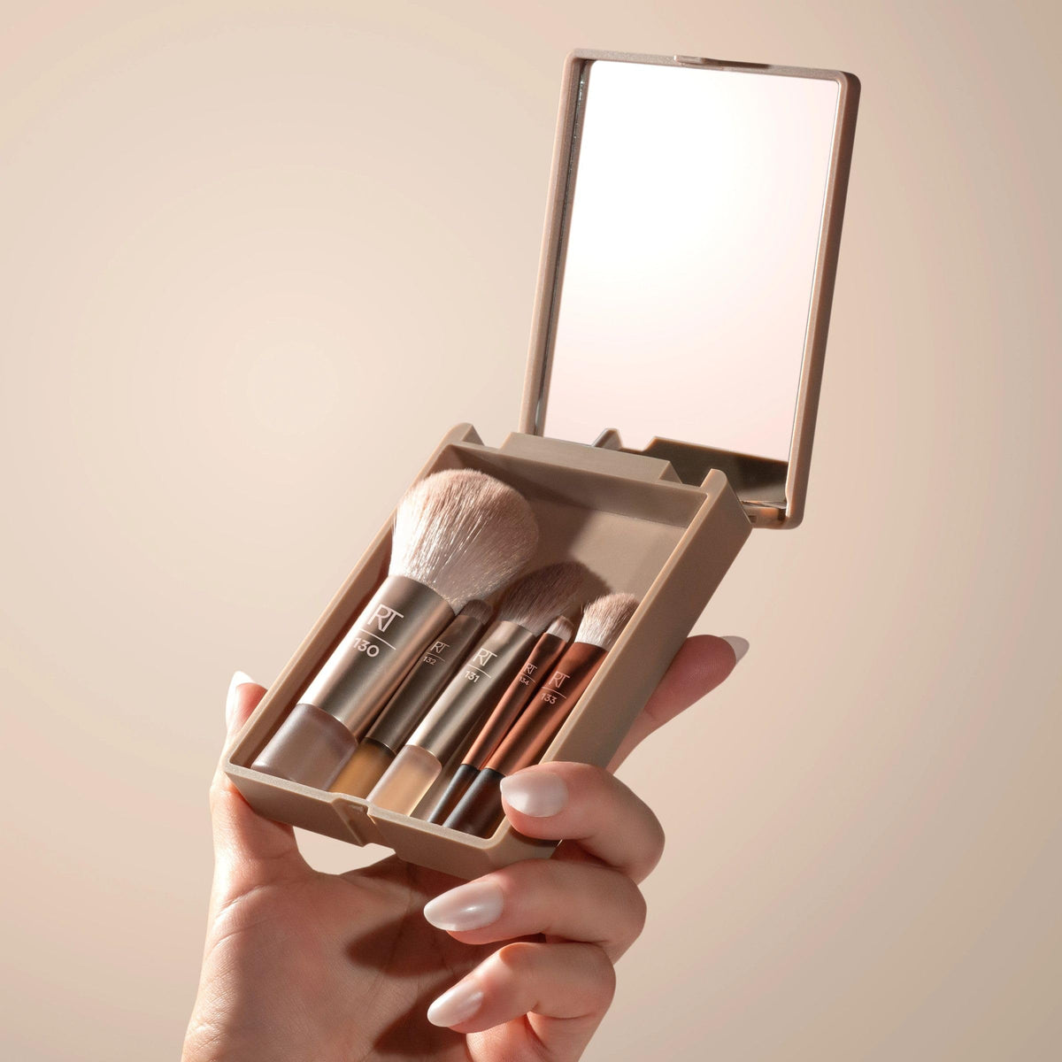 Real Techniques brush in hand to show mini size and easy travel-friendly scale