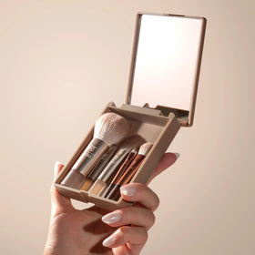 Real Techniques brush in hand to show mini size and easy travel-friendly scale