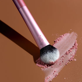 Real Techniques RT 449 applying highlighter to cheekbone for subtle glow