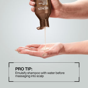 Redken shampoo in hand applied to wet curly hair for improved manageability