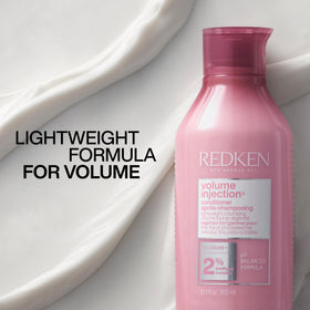 Redken conditioner on bathroom shelf staged with styling tools, suggests salon-finish results