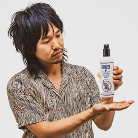 Reuzel bottle in hand showing 3.38 oz scale and travel-friendly benefit