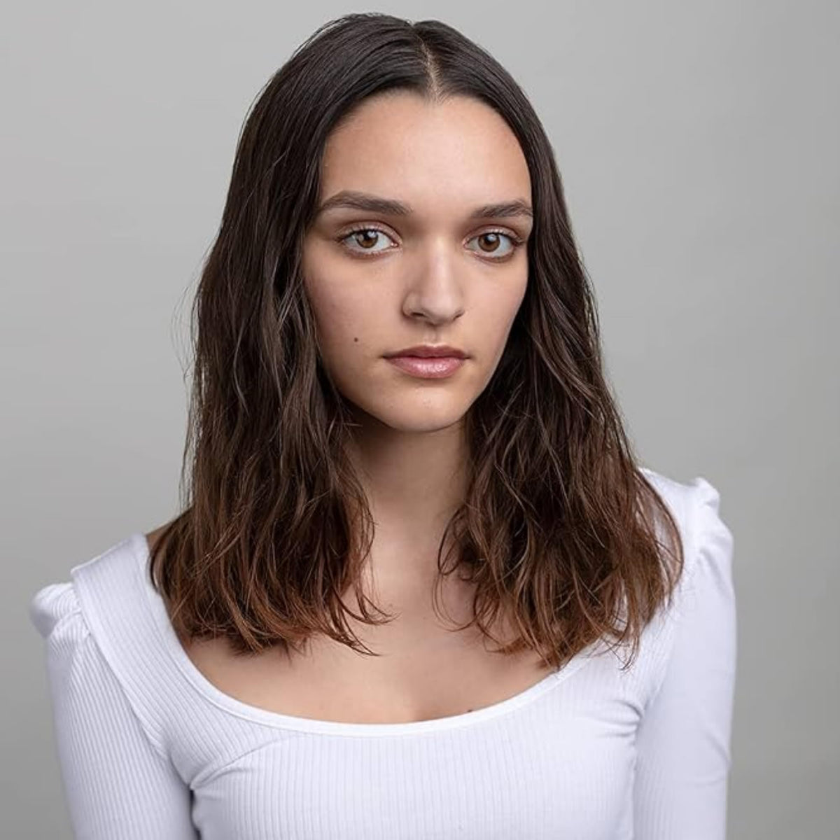 R+Co model applying balm to curls to show definition and frizz control benefit