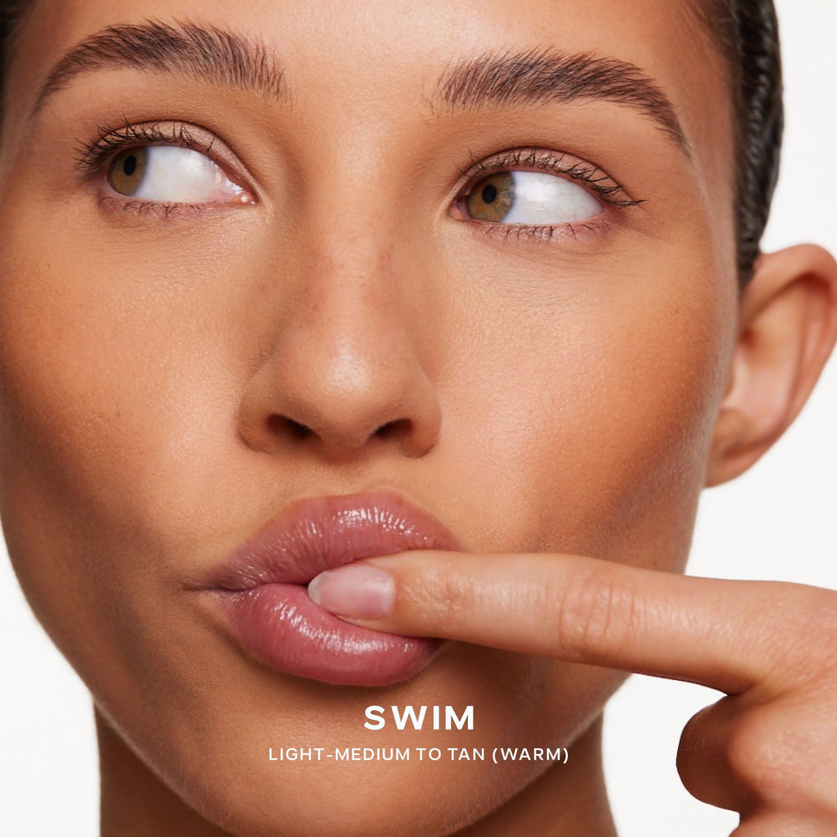 Saie Dew Bronze being applied to cheek for instant sun‑kissed warmth