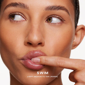 Saie Dew Bronze being applied to cheek for instant sun‑kissed warmth