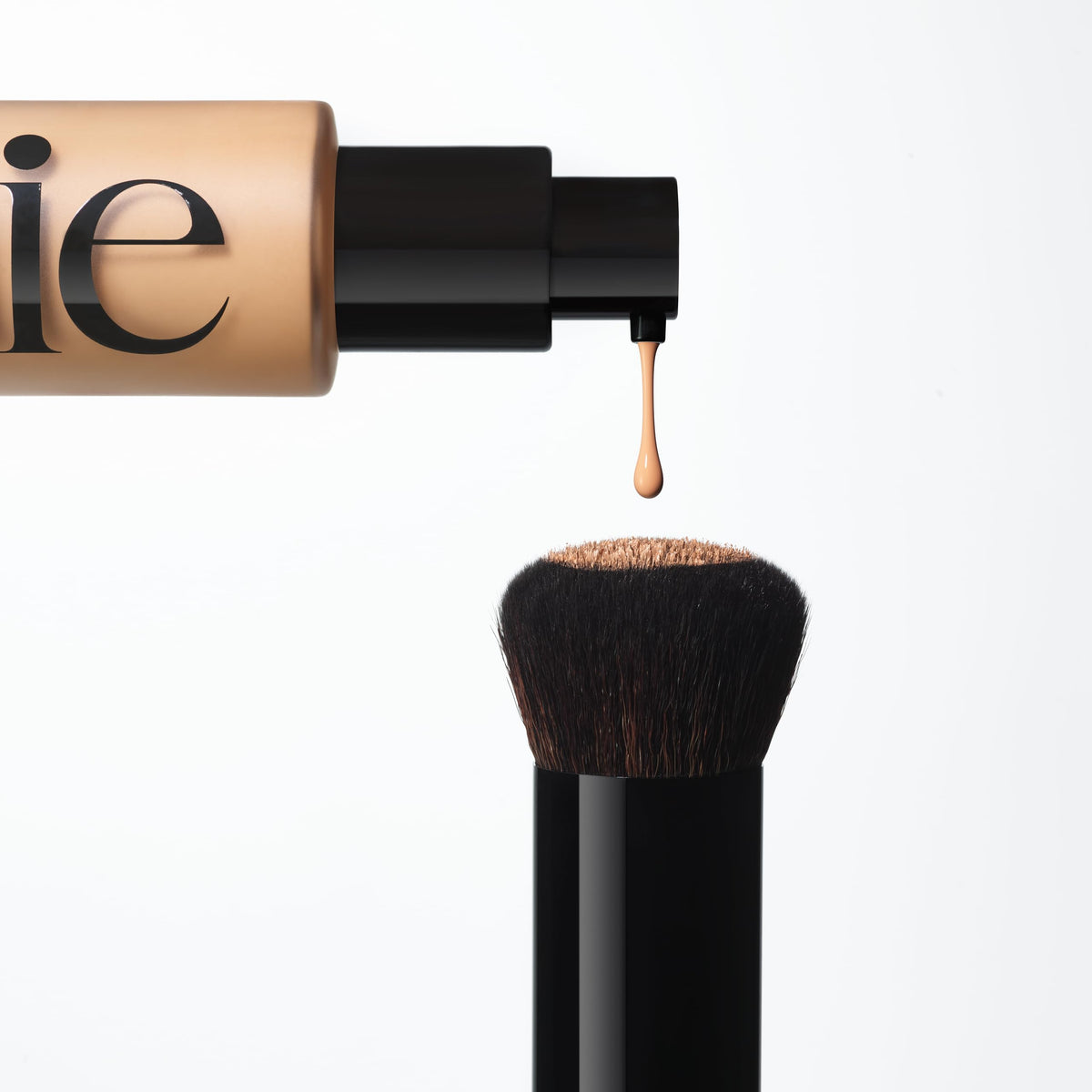 Saie brush next to foundation pump showing scale and product compatibility